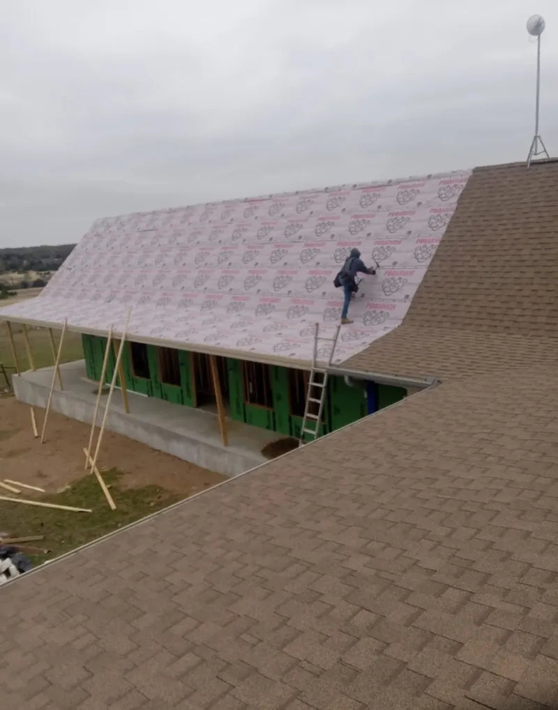 Worker preparing underlayment for a metal roof installation in Anchorage